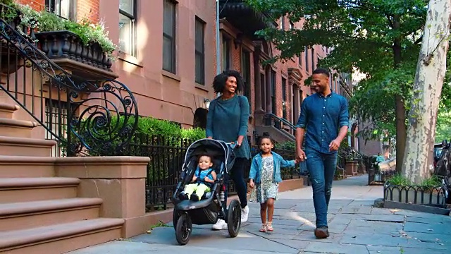 一个年轻的黑人家庭推着婴儿车走在布鲁克林大街上视频素材