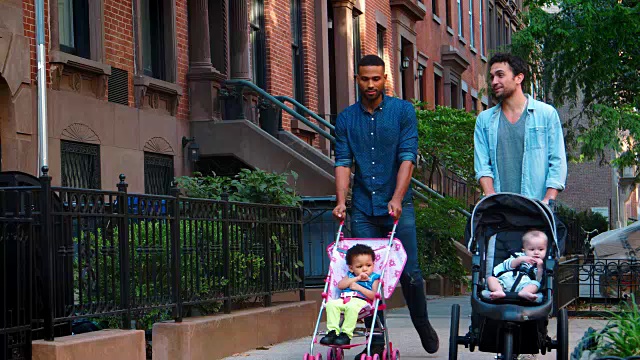 两个父亲朋友推着婴儿车走在街上视频素材
