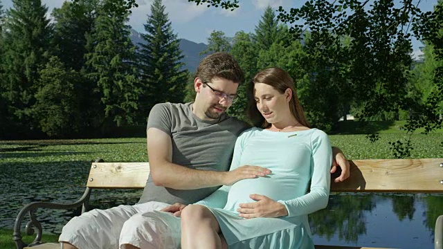 图为:在公园里，兴奋的爸爸正在揉宝宝妈妈怀孕的肚子。视频下载