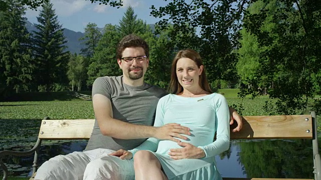 肖像:可爱的期待年轻夫妇愉快地坐在木凳上微笑视频下载