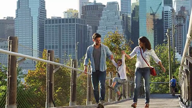 一对年轻夫妇和女儿走在曼哈顿的人行桥上视频购买