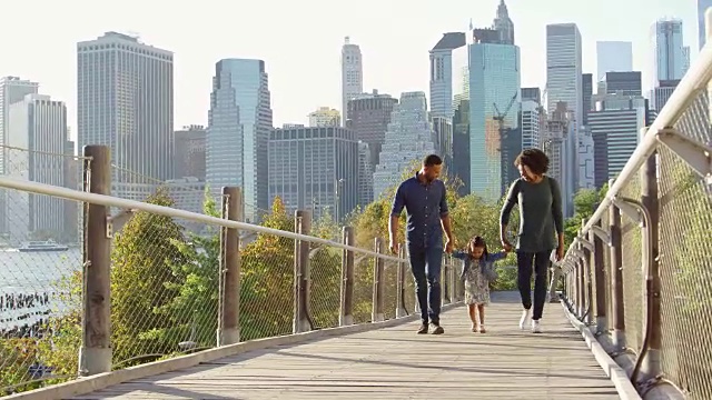 一对黑人夫妇和女儿走在曼哈顿的人行桥上视频素材