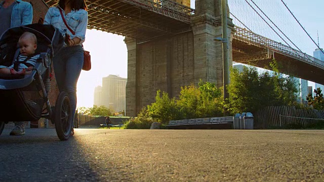 一个年轻的家庭带着两个孩子在曼哈顿的桥下散步视频素材