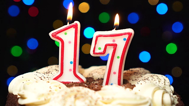 在蛋糕上放17号——17岁生日蜡烛燃烧——最后吹灭。颜色模糊的背景视频下载