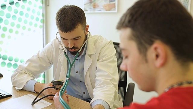 年轻男医生用医疗仪器测量病人的血压视频素材