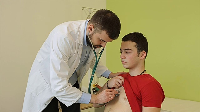 医生用听诊器听一个生病男孩的肺视频下载