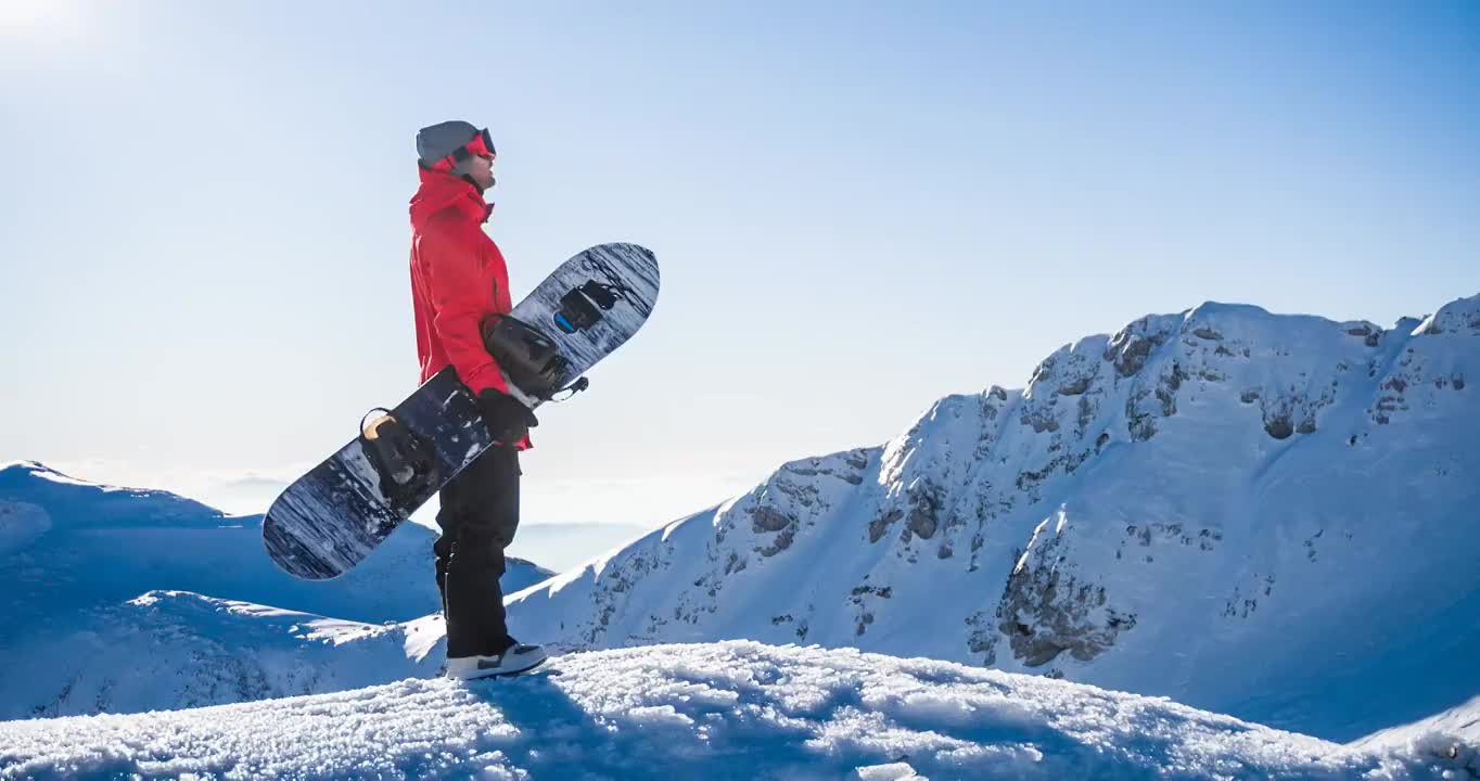 在一个阳光明媚的日子里，在山顶上玩滑雪板，欣赏冬天的风景视频素材