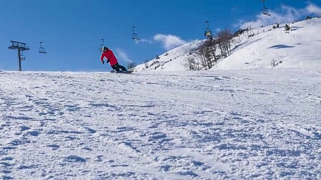 滑雪者在滑雪坡上转弯，身后留下一团粉雪，背景是滑雪缆车视频素材