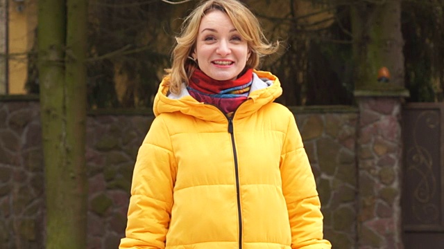 30-40岁的美女真诚地笑。她穿着一件亮黄色的夹克，戴着一条红色的围巾视频素材