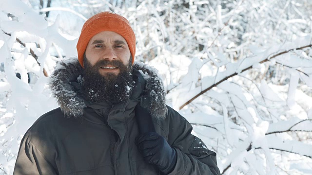 一名男子在一个冬日下雪天的户外对着镜头微笑和挥手视频素材