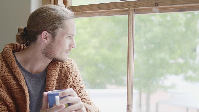 一个男人一边喝着咖啡，一边透过窗户往外看视频素材