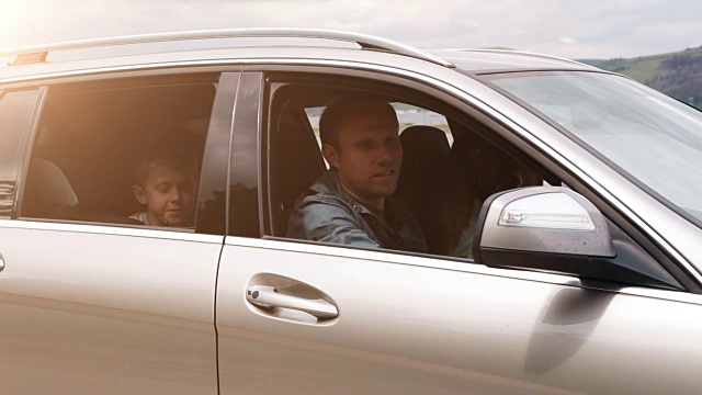 家人乘汽车离开:快乐的男孩从敞开的窗户向我们挥手视频素材
