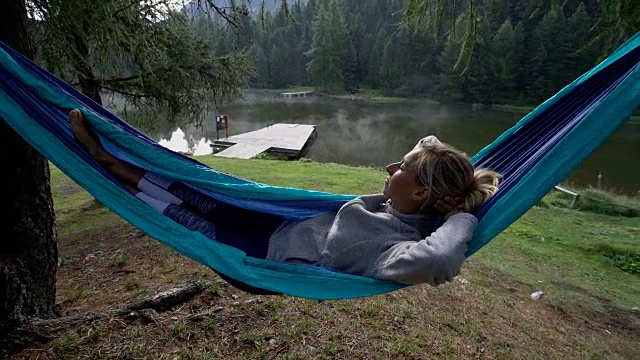 年轻女子在瑞士湖边的吊床上休息视频下载