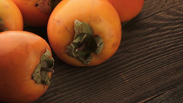 木桌上放着鲜橙柿子。美味的橘子柿子。视频下载