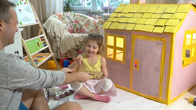 爸爸给了快乐的小女孩一把新纸板屋的钥匙视频素材