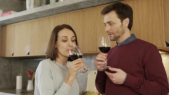微笑的夫妇在厨房喝红酒视频素材