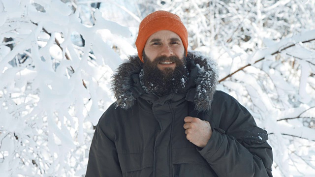 一名男子在一个冬日下雪天的户外对着镜头微笑和挥手视频素材