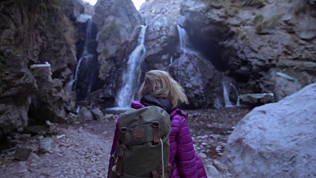 探索荒野。欣赏山间瀑布的女子视频下载