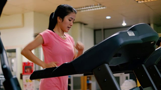 在健身房或运动俱乐部跑步机上跑步的年轻亚洲女性视频素材