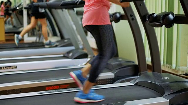 在健身房或运动俱乐部跑步机上跑步的年轻亚洲女性视频素材