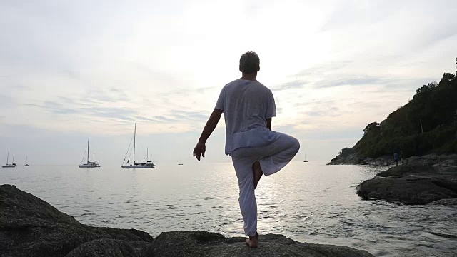 男子在海岸的石板上表演瑜伽动作视频素材