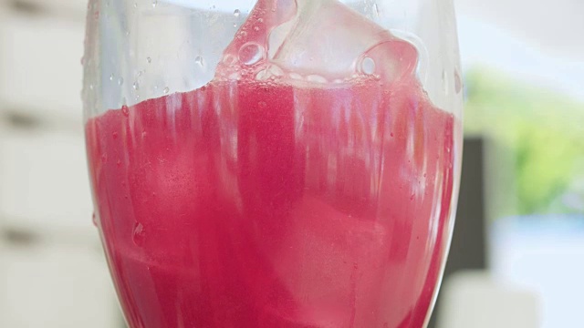 向玻璃杯中倒入冰的粉红色鸡尾酒的微距镜头视频下载