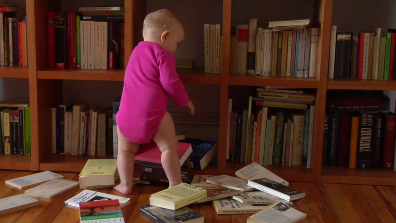 WS德国柏林，一名12-17个月大的女婴从书架上乱扔书视频下载