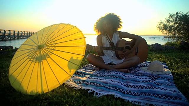 非裔美国妇女在海滩野餐时弹吉他视频下载