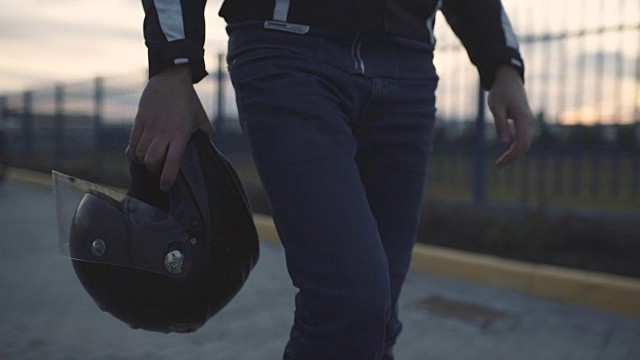 年轻迷人的摩托车手戴着黑色头盔在街上。男人摩托车骑士视频素材