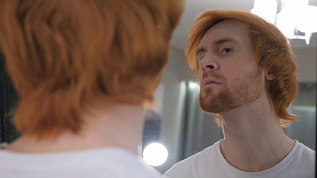 红头发胡子男在镜子里检查他的牙齿视频素材