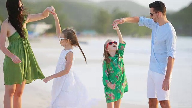 父母和可爱的两个孩子有很多乐趣在他们的暑假在海滩上。四口之家相爱。幸福和美丽视频素材