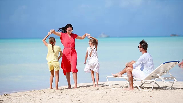 年轻的家庭度假有很多乐趣。妈妈和她漂亮的孩子们在沙滩上跳舞视频素材