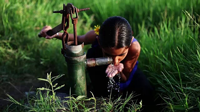 小女孩在绿色的田野边喝水视频素材