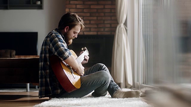一个男人坐在地板上，在家弹吉他视频下载