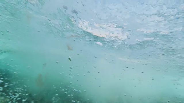 水下慢动作:冲浪者骑在冲浪板上穿过充满泡沫的海洋视频素材