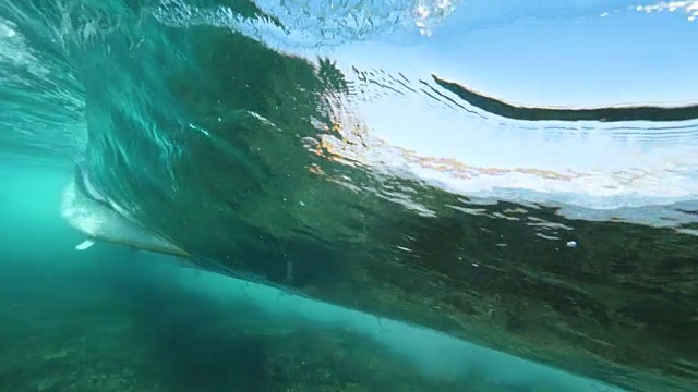 水下慢动作冲浪者在冲浪板上在清澈的海洋中冲浪。视频素材