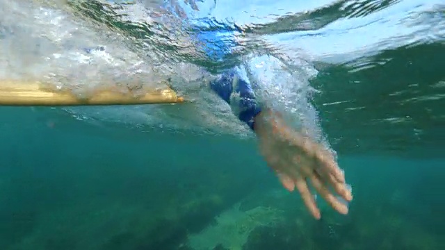 水下慢动作:冲浪者划着他的冲浪板在美丽的海洋视频素材