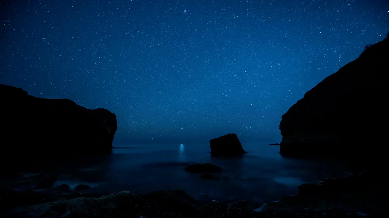 延时。星星在多岩石的海岸上空划过视频下载