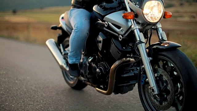 日落时分，摩托车手在空旷的路上骑着摩托车视频素材