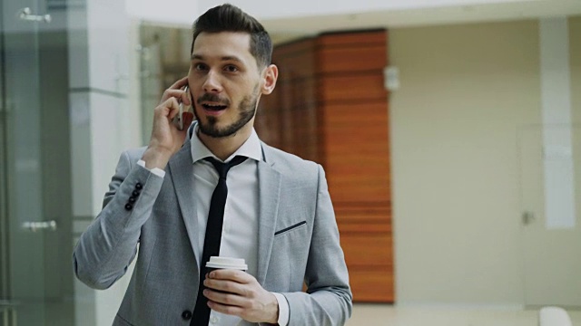 Stedicam拍下了兴高采烈的商人与智能手机交谈、在现代办公大厅里行走的画面视频下载