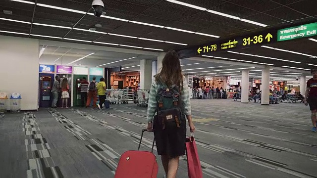 带着红色行李的女乘客在机场候机楼行走视频素材