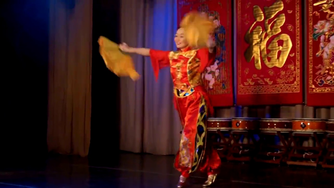 亚洲妇女穿着中国传统的红色服装，拿着大大的黄色扇子跳舞。视频素材