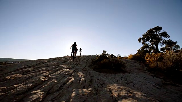 三个女人骑着山地自行车攀登岩石地形。视频素材