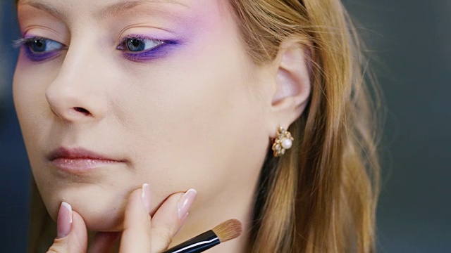 一个年轻的蓝眼睛女人正在脸上化妆视频素材