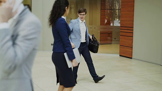 一个疯狂的商人拿着公文包在现代化的大厅里跳舞，而他的同事们正在惊讶地看着他视频素材
