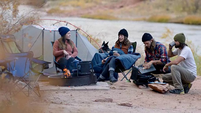 一群朋友在露营旅行聊天篝火和烹饪便携式烧烤。视频素材