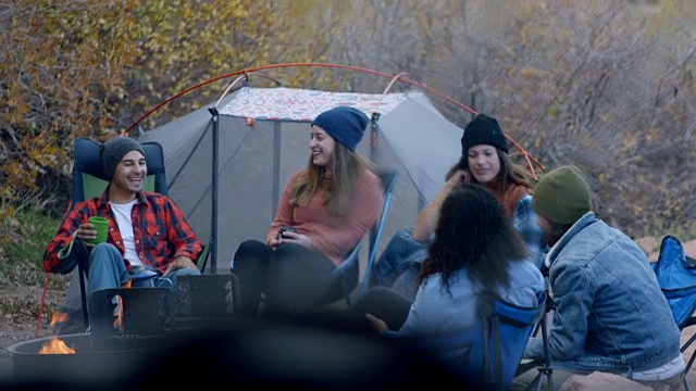 野营时一群喜欢冒险的朋友围坐在火坑边聊天。视频素材