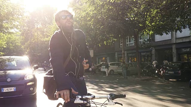 在阳光明媚的日子里，年轻的潮男骑着自行车在罗马市中心的道路上等着红绿灯，戴着太阳镜视频素材