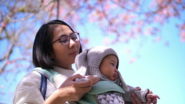 SLO MO亚洲女人在樱花下玩她的孩子视频素材