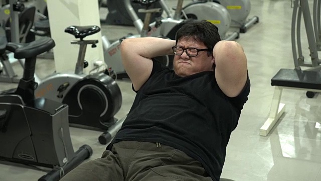 在健身房做仰卧起坐的胖子视频素材